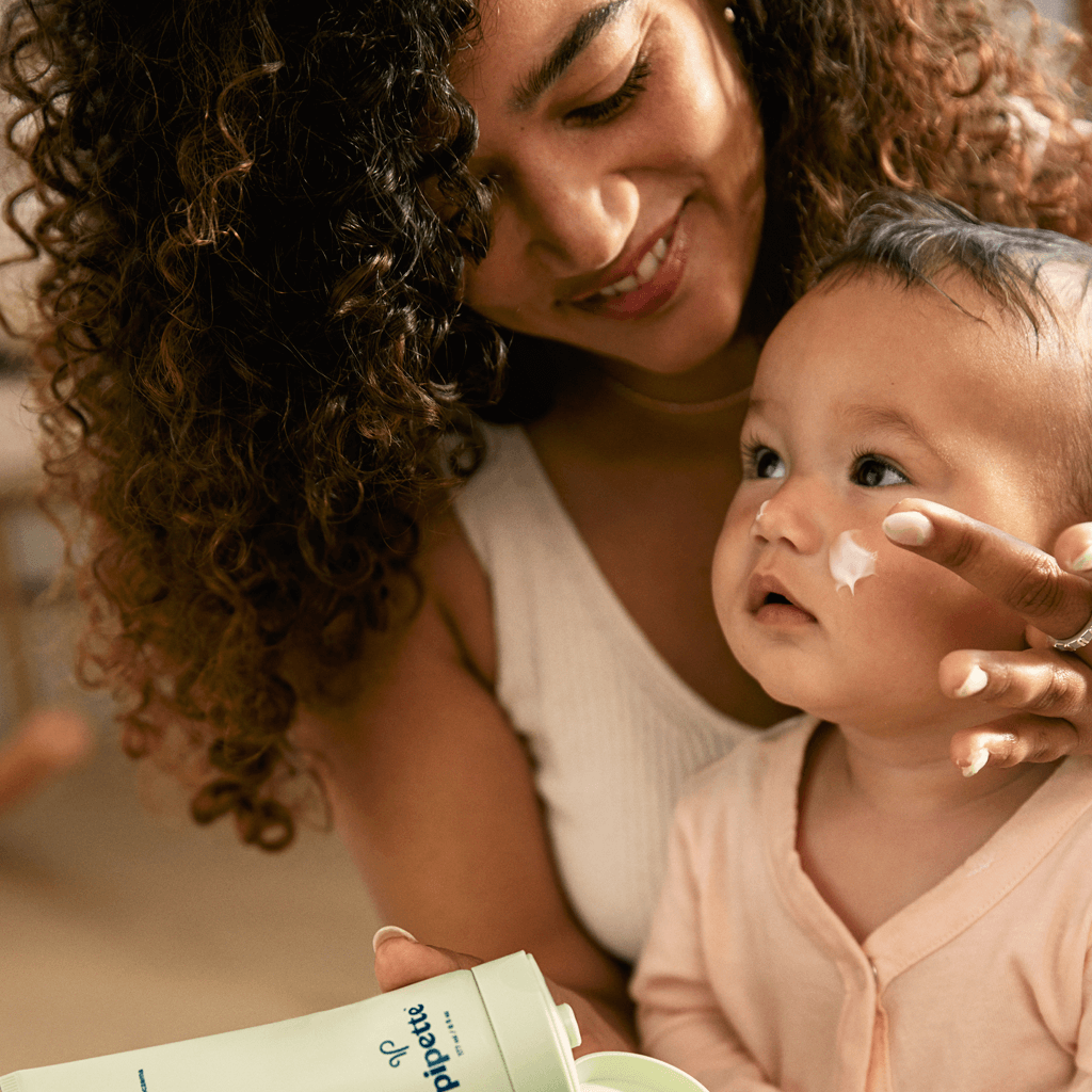 Mom applying Eczema Lotion to baby's cheek.