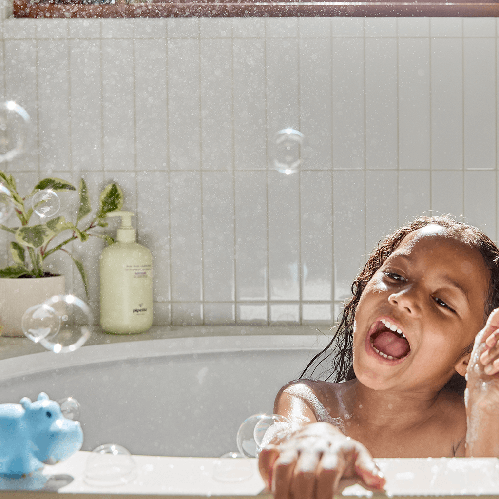 kid in bubble bath playing with hippo toy