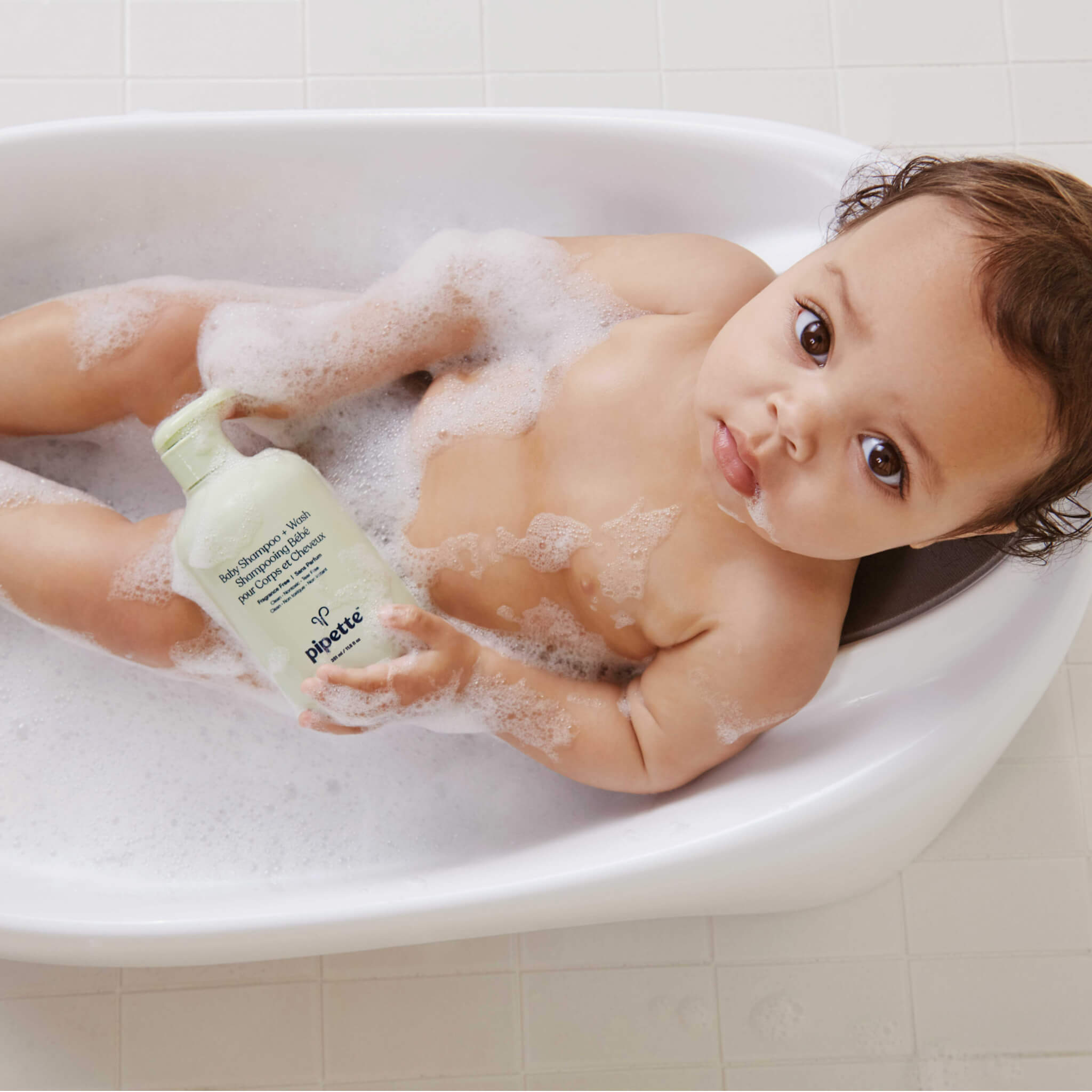 baby with baby shampoo in her hands